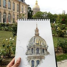 a hand holding up a drawing of a building