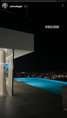 an outdoor swimming pool at night with curtains on the side