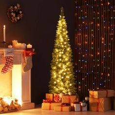 a lit christmas tree in front of a fireplace with presents on the floor next to it