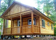 a small wooden cabin in the woods with porches and stairs leading up to it