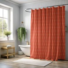 an orange shower curtain in a bathroom next to a bathtub and window with potted plants