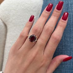 a woman's hand with red nails and a ring