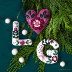 a christmas ornament with the word love hanging from it's side next to a pine branch