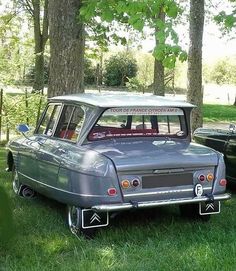 two old cars are parked in the grass