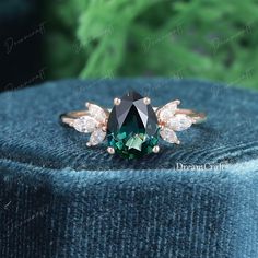 an emerald colored diamond ring with two white diamonds on the top and one green stone in the middle