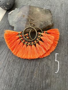 Unique fun colorful and powerful tassel earrings. Made in fan shapes with the red/orange tones. You can choose between 5 different pairs. 3 of them are made with a round plastic base which from where tassels hang and are hold with some brass beads and wax cord. 2 of them are made with a brass wire spiral shape from where the tassels hang with wax cord holding the tassels. Each pair is unique and fun. They are all super light and easy to wear. The earrings with the round piece in the middle are 6 Adjustable Orange Tassel Earrings, Orange Tassel Dangle Earrings, Beach Dangle Chandelier Earrings With Tassels, Bohemian Orange Fringe Earrings, Orange Beaded Tassel Earrings As Gift, Adjustable Beaded Tassel Earrings, Orange Fringe Tassel Earrings For Gift, Orange Fringe Earrings As A Gift, Orange Fringe Earrings As Gift