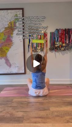 a woman sitting on top of a yoga mat in front of a wall with a map