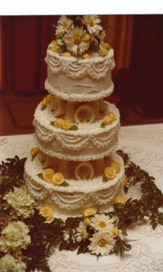 a three tiered wedding cake with flowers on the top and bottom is sitting on a lace tablecloth