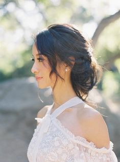 a woman in a white dress looking off to the side with trees in the background