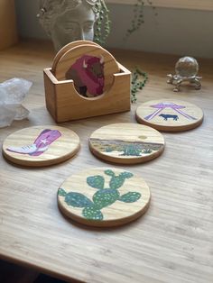 four wooden coasters with different designs on them sitting on a table next to a statue