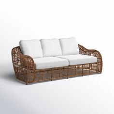 a wicker couch with white cushions on a white background in front of an empty wall