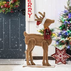 a wooden reindeer standing next to a christmas tree