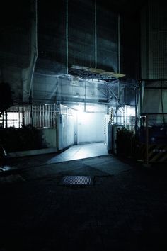 an empty parking garage at night with the door open and light shining on it's side