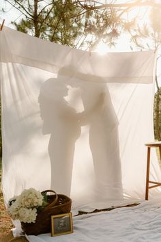 two people are kissing in front of a white canopy with flowers on the bed and an empty basket