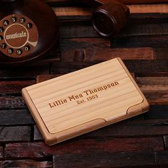 a wooden business card case sitting on top of a table next to an old phone