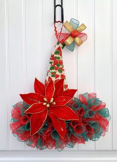 a red and green christmas wreath hanging on the side of a white door with scissors