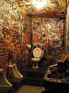 a bathroom with graffiti on the walls and two urinals next to each other