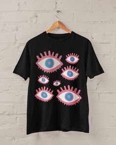 Grunge Eyes T-shirt Printed on a super soft, cotton tee Dispatched in 5 working days or sooner Unisex Free UK delivery Material: 100% ringspun cotton. Chest (to fit): S  34/36   M  38   L  40/42   XL  44/46   XXL  48/50 ECO-FRIENDLY Each garment is made to order, reducing extra material and energy that would be otherwise wasted We use DTG printing process which is easier on the environment than screen-printing Our ink is bright and also eco-friendly. Do not tumble dry. Wash at 30 degrees c, insi Emo Black T-shirt With Graphic Design, Emo Crew Neck T-shirt With Graffiti Print, Halloween Pink T-shirt With Screen Print, Pink Halloween T-shirt With Screen Print, Pink Cotton Emo T-shirt, Alternative Funny Print T-shirt For Streetwear, Black Alternative Style Top For Fans, Edgy Pink T-shirt With Graphic Print, Alternative Black T-shirt With Front Print