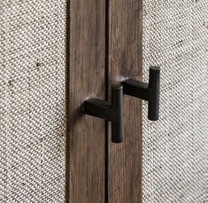 a close up of a door handle on a wooden door with fabric in the background