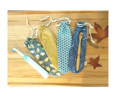 three ties and a toothbrush on a wooden floor with leaves around them, one is blue and the other is yellow