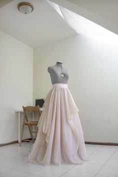 a mannequin is dressed up in a dress on a display table with a chair