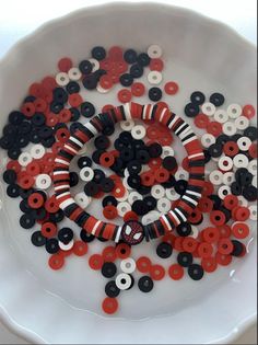 a white bowl filled with black, red and white buttons on top of a table