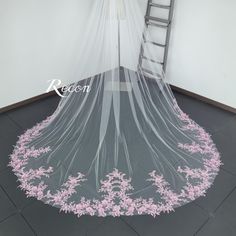 a wedding veil with pink flowers on it and a ladder in the background that says reception