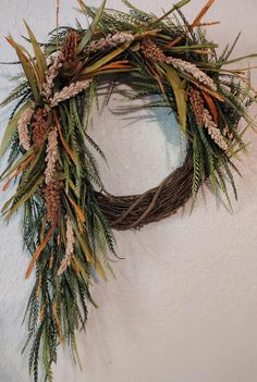 a wreath is hanging on the wall with pine cones and evergreen needles in it's center