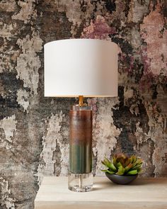 a table with a lamp and succulents on it in front of a wall