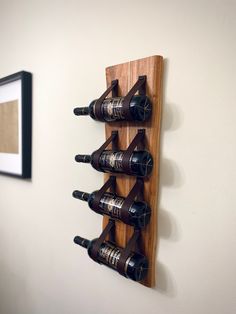 a wooden wine rack with six bottles on it and a framed picture in the background