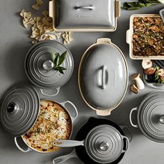 various pots and pans are arranged on a gray surface with food in the middle