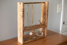 a wooden frame with jewelry hanging from it's sides on a table next to a door