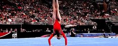 a person doing a handstand on a tennis court in front of an audience