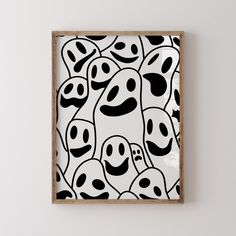 a black and white painting with faces on it in a wooden frame hanging on the wall