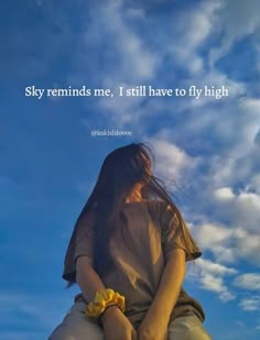 a woman sitting on top of a rock under a blue sky