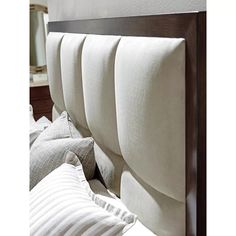 the headboard of a bed with white sheets and pillows