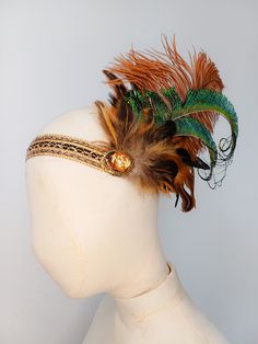 A beautiful Flapper-style headband with a bronze and gold band that sits across the forehead, bronze jewel embellishment, soft brown feathers and a statement curled peacock feather. At the back, the band has a section of black sequinned elastic, allowing it to fit most head sizes and making it comfortable to wear. Perfect for adding that finishing touch to your party outfit or performance costume. The width of the band is approximately 2.5cm/1 inch. This piece has been designed and made by the l Gold Headband Headpieces For Carnival, Vintage Adjustable Feather Headpieces, Vintage Adjustable Headpieces With Feathers, Adjustable Vintage Headpieces With Feathers, Adjustable Feather Headband, Gatsby Style Feather Headband, Bohemian Carnival Headband, Adjustable Feather Trim Headband, Adjustable Gold Hair Accessories For Festivals