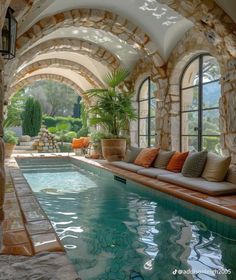 an indoor swimming pool surrounded by stone arches and arched doorways, with seating on either side