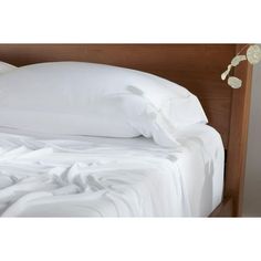 an unmade bed with white sheets and pillows