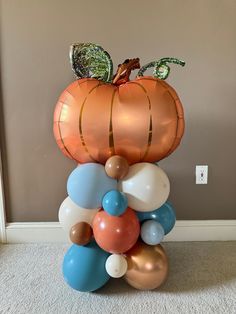 an orange pumpkin sitting on top of balloons in the middle of a room with white carpet