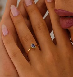 a woman's hand with a ring on it and her finger next to her face