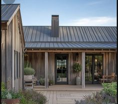 a wooden building with metal roofing and two doors on the front porch, surrounded by greenery