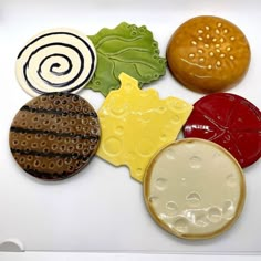 four different colored cookies sitting on top of a white table next to eachother