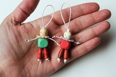 two small wooden toy figures hanging from strings in the palm of someone's hand