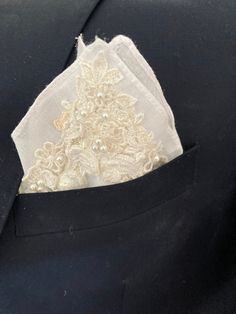 a white piece of cloth in the pocket of a black suit with lace on it