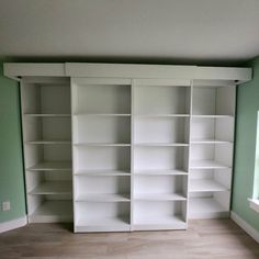 an empty room with white bookcases and green walls