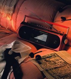 an old radio sitting on top of a bed next to pillows