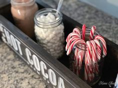 some candy canes and marshmallows in a container on a counter top