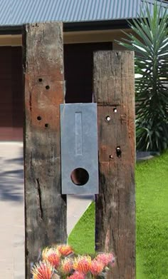 a bird house built into the side of a wooden fence with flowers in front of it