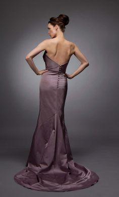 a woman in a long purple dress with her back to the camera, looking down